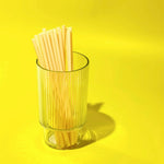 Glass filled with tall bamboo fiber drinking straws. 