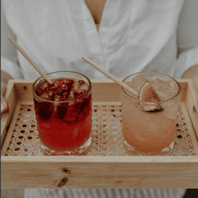 Bartender presenting two wheat stem cocktails